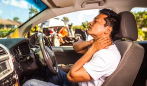 A worried man in his car holds his neck in pain while recalling the crash, illustrating the delayed onset of injury symptoms after an Illinois accident.